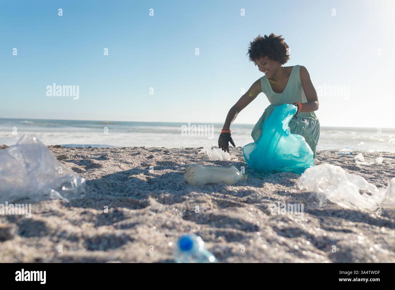 Pulizia della spiaggia, donna che raccoglie rifiuti di plastica in sacchetti blu, promuove la cura dell'ambiente, copia spa Foto Stock