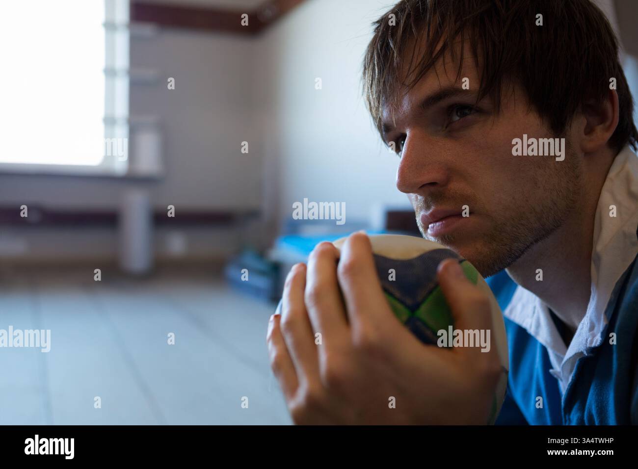 Uomo concentrato che tiene la palla di cricket, contempla strategia in una struttura sportiva, copia spazio Foto Stock