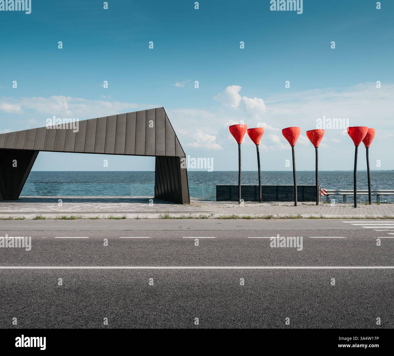 Fermata dell'autobus vicino al mare con sculture di papavero. Oggetti d'arte moderna, luci stradali a forma di fiore di papavero alla fermata dell'autobus con vista. Foto Stock