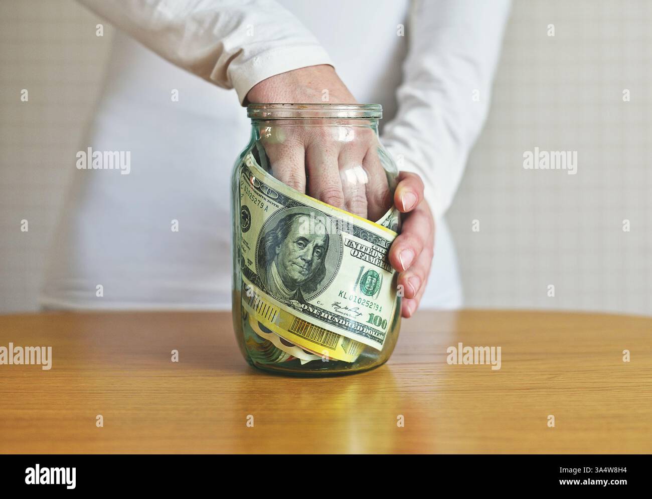 mano femminile in un vaso di vetro con soldi Foto Stock