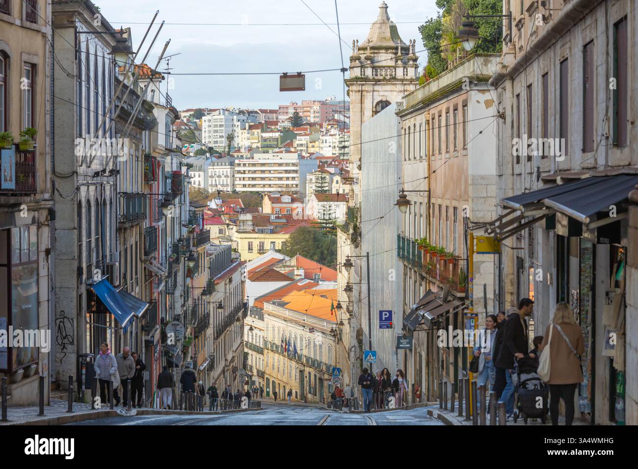 . Lisbona Street in discesa, gente che cammina per la strada e colorato paesaggio urbano in lontananza. Foto Stock