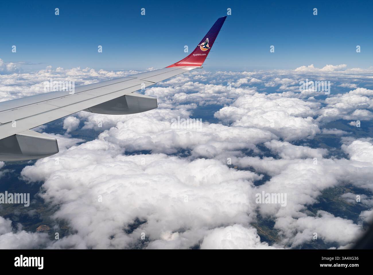 Flyairlink.com, logo di Airlink, una compagnia aerea regionale sudafricana, seenon una punta alare rovesciata in volo sopra nuvole bianche Foto Stock