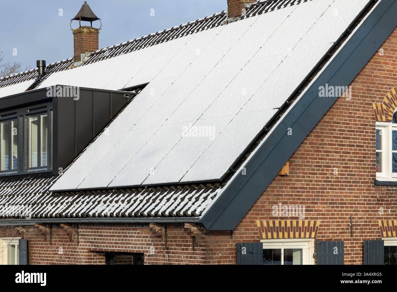 Pannelli solari privati con neve sul tetto di una vecchia casa storica e monumentale in inverno. Foto Stock