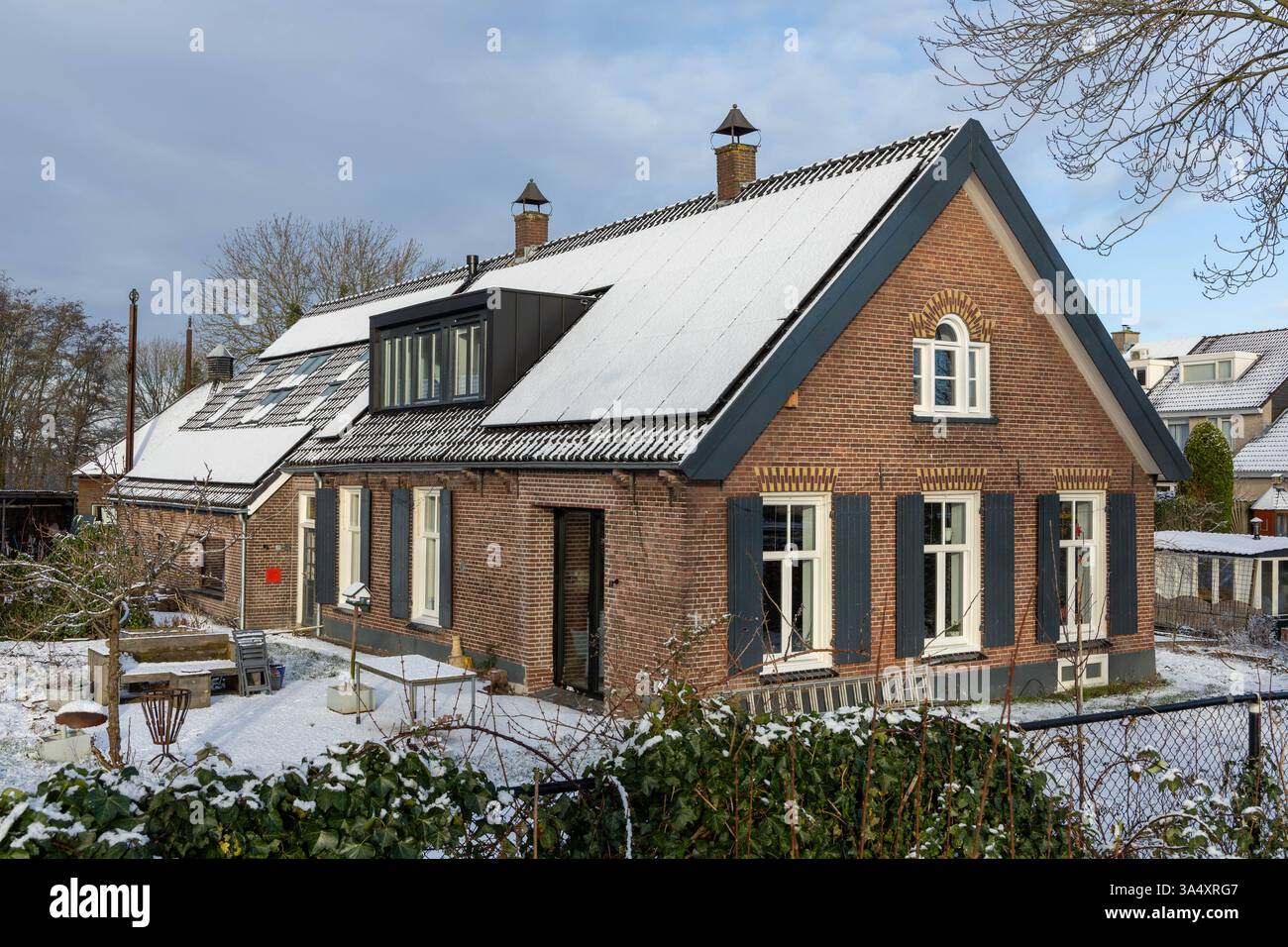 Pannelli solari privati con neve sul tetto di una vecchia casa storica e monumentale in inverno. Foto Stock