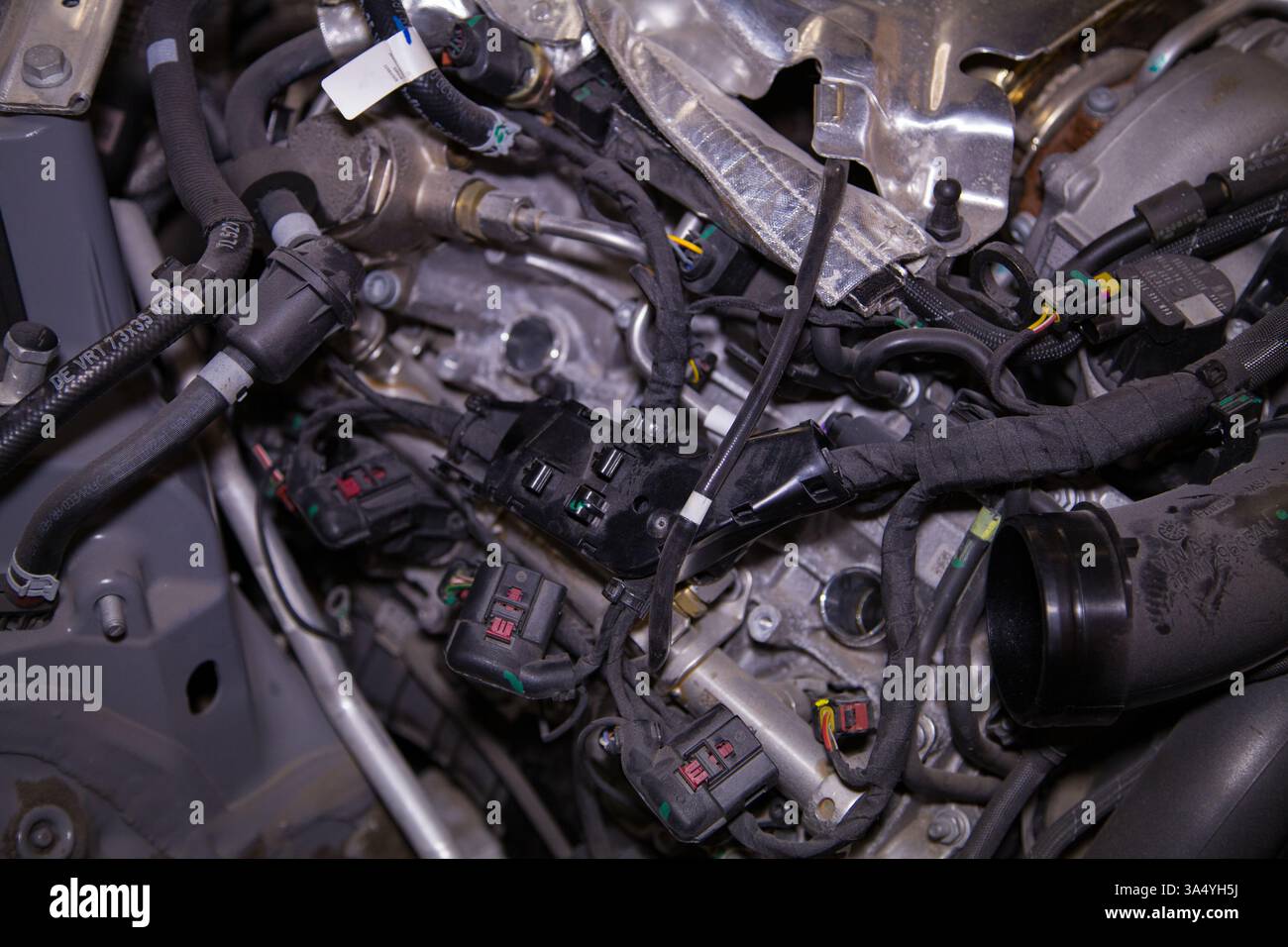 Vano motore parzialmente smontato di una vettura con il coperchio motore rimosso, le candele rimosse e il cablaggio esposto Foto Stock