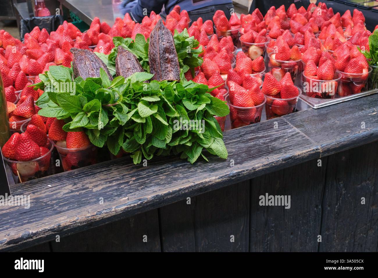 Tazze di plastica di fragole fresche in vendita con mazzi di menta, Borough Market, Londra Foto Stock