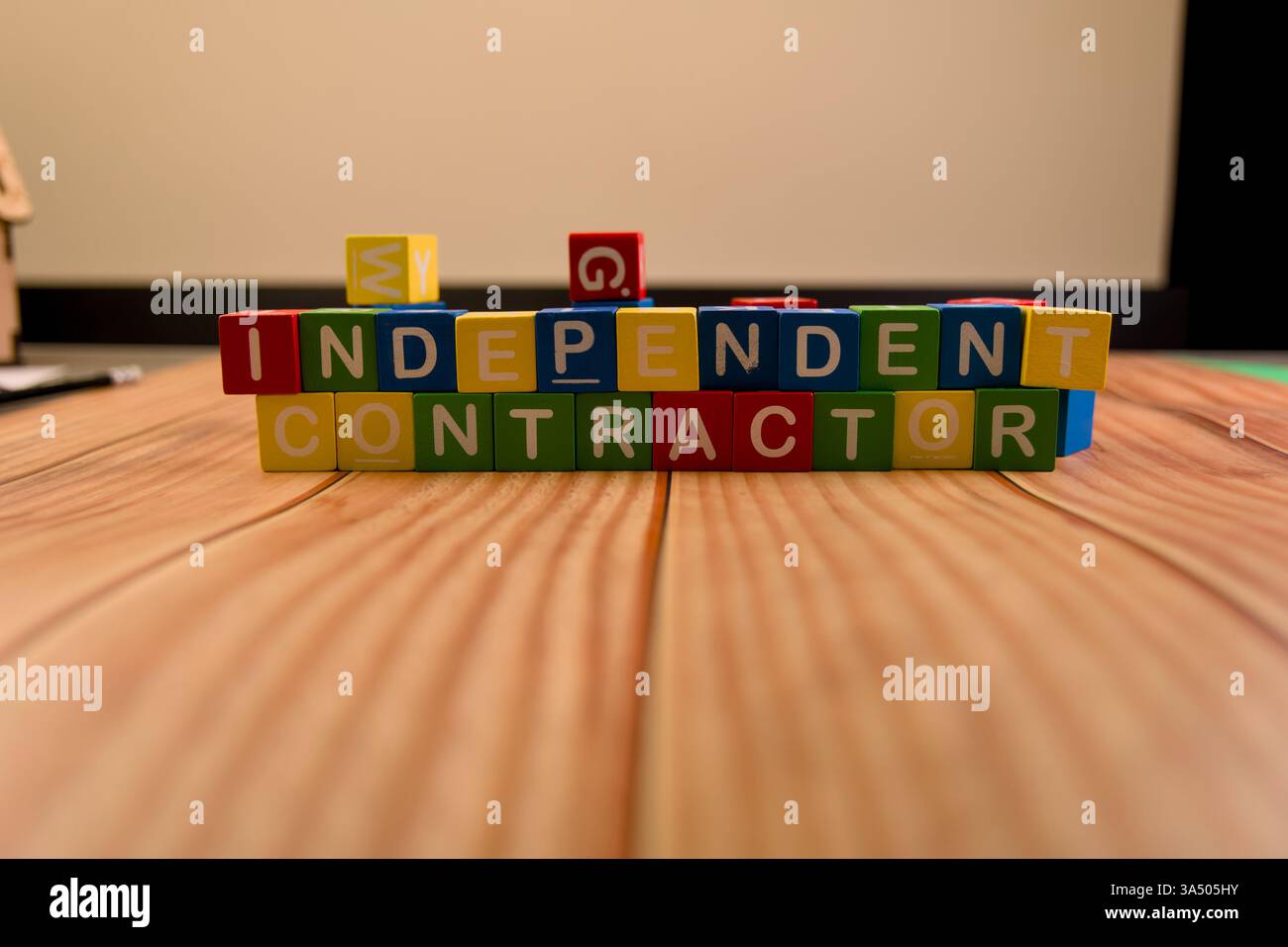 Blocchi colorati disposti per indicare appaltatori indipendenti su un piano di legno in un ufficio. Foto Stock