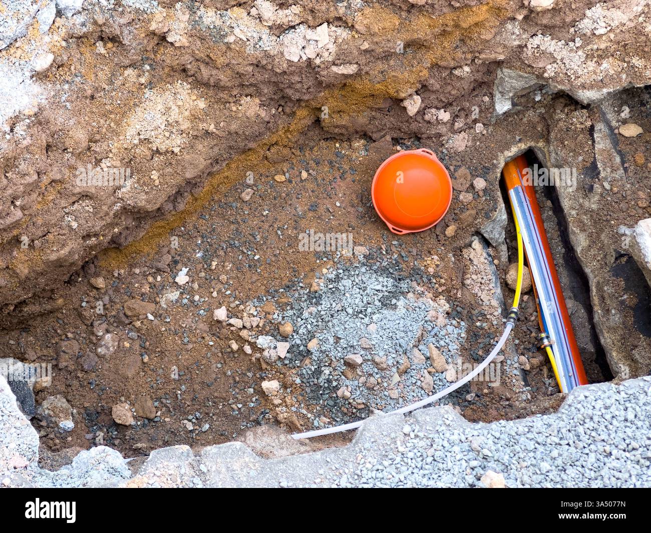 Posa di un cavo in fibra ottica per Internet veloce in strada Foto Stock