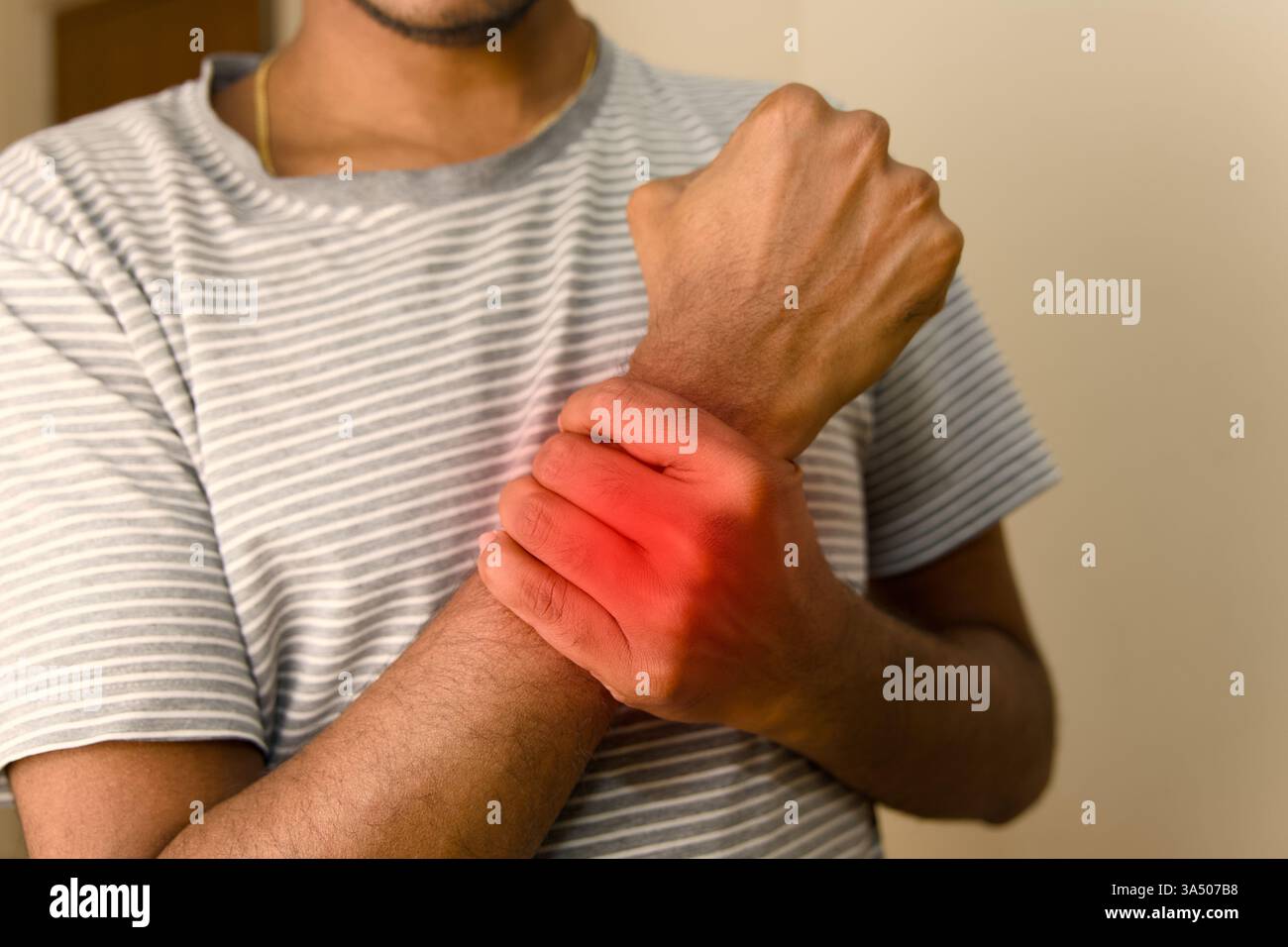 Una persona tiene il polso in disagio, mostrando un'irritazione visibile durante un momento occasionale all'interno. Foto Stock Una persona tiene il polso in disagio, mostrando un'irritazione visibile durante un momento occasionale all'interno. Foto Stock