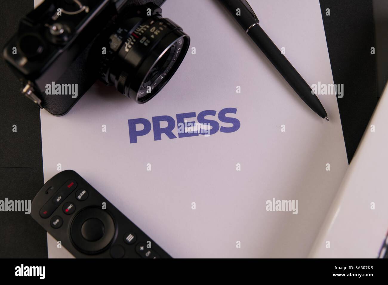Configurazione della scrivania con materiali per la stampa, una fotocamera e un telecomando, ideale per attività multimediali. Foto Stock