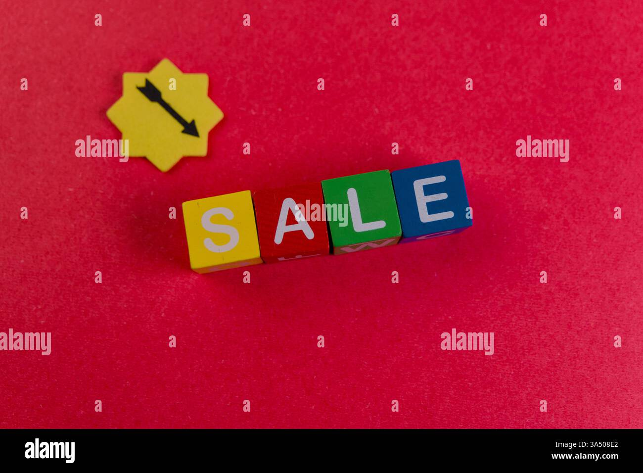 I blocchi dai colori vivaci fanno la vendita su una superficie rossa, incoraggiando gli acquirenti a usufruire di sconti e offerte. Foto Stock