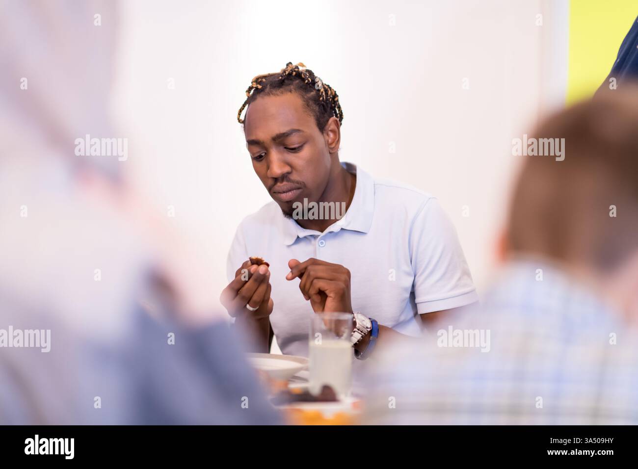 Uomo afroamericano che condivide una cena iftar con una moderna famiglia musulmana multietnica a casa durante il Ramadan. Un ambiente caldo e incentrato sulla famiglia che mette in risalto diversità, cultura e ospitalità. Ideale per campagne di marketing Ramadan, cene halal e feste casalinghe. Foto Stock