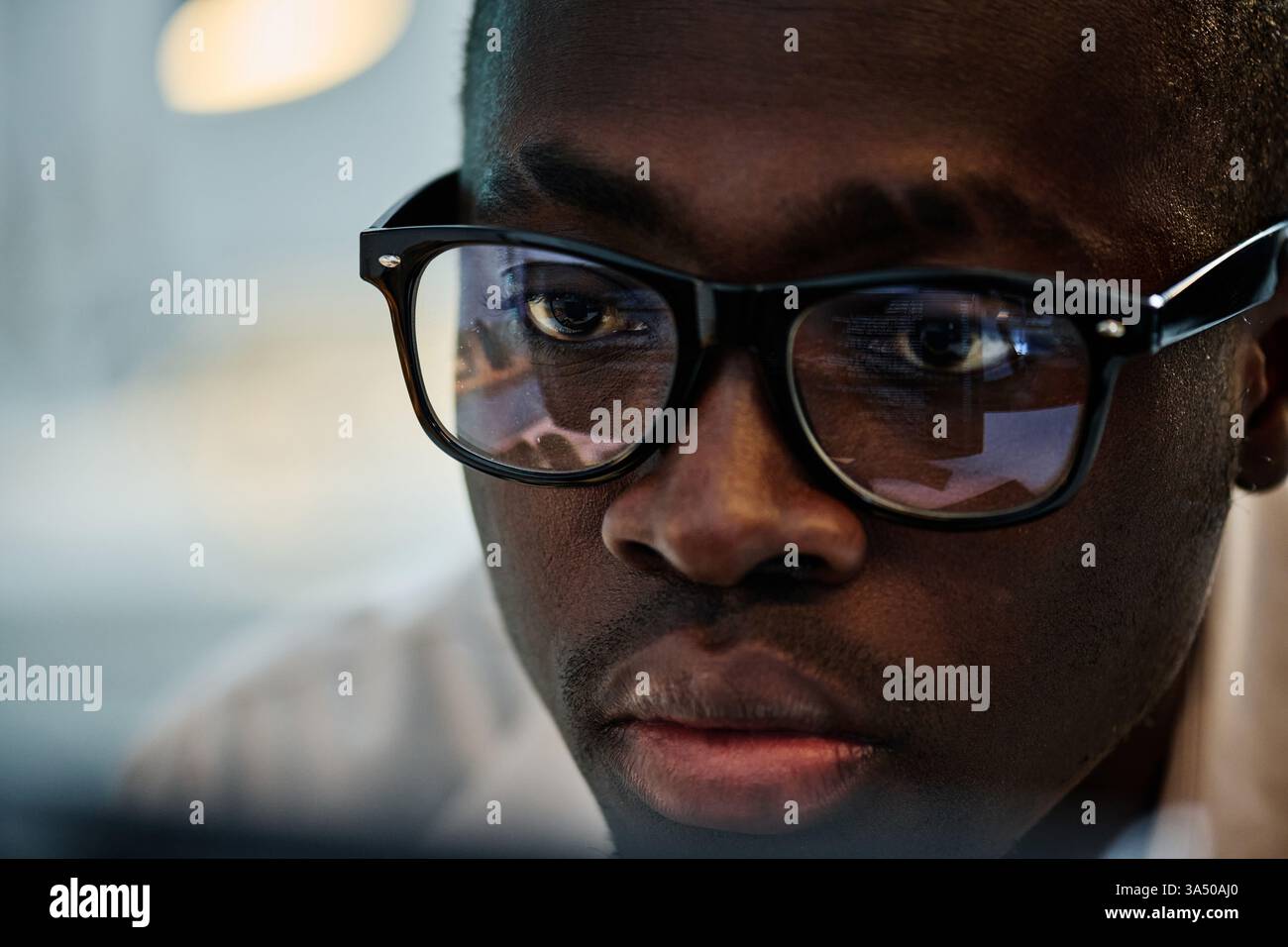 Programmatore maschio Black Focused in occhiali che esamina i codici del computer in ufficio Foto Stock