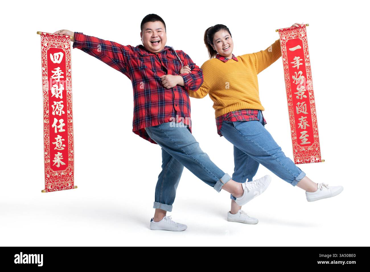 Allegra coppia cinese di grandi dimensioni che tiene accoppiati cinesi in uno studio su sfondo bianco. La posa festosa cattura la gioia e la celebrazione della grafica del Capodanno cinese. Ideale per campagne culturali, saluti e feste tradizionali. Foto Stock