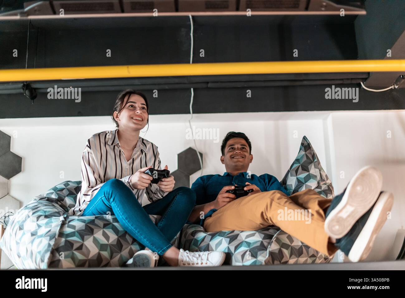 Momenti di relax in ufficio all'avvio mentre i colleghi giocano a un videogame per computer durante una pausa. Una scena creativa e orientata al lavoro di squadra adatta a contenuti di innovazione e cultura aziendale. Foto Stock