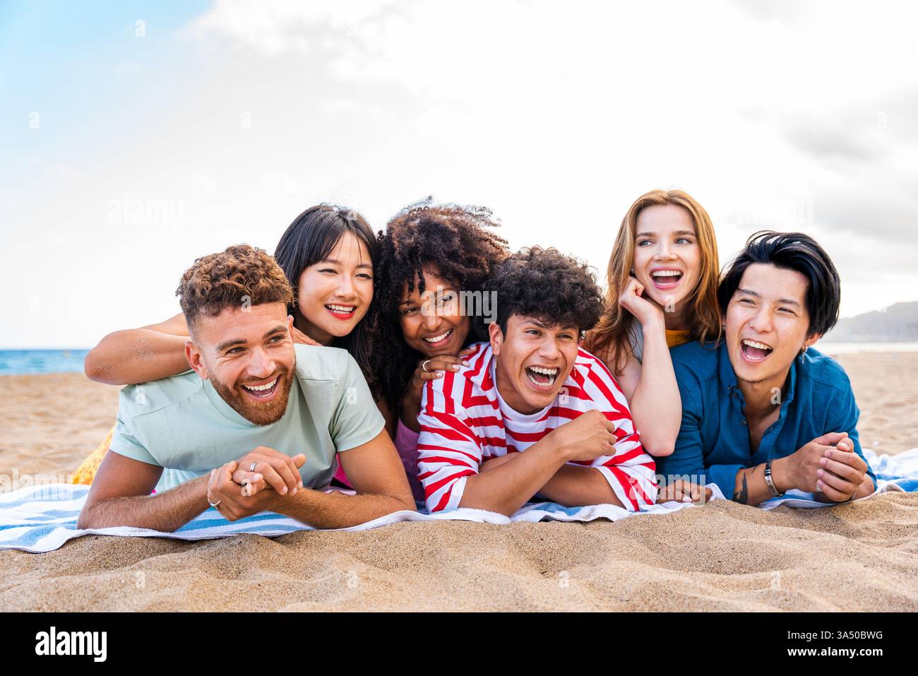 Un gruppo di giovani e allegri amici di diverse origini che si legano all'aria aperta in una giornata di sole d'estate. Indossano abiti estivi casual e trasudano felicità, perfetti per viaggi e campagne di lifestyle. Foto Stock