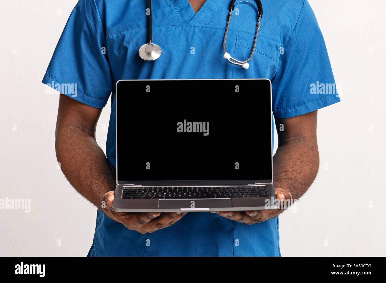 Primo piano delle mani di un medico afroamericano che presenta uno schermo vuoto per laptop su uno sfondo bianco. Lo spazio di copia lo rende ideale per i mockup di siti Web medici, il branding sanitario e la grafica di telemedicina. Immagini professionali e pulite adatte a servizi clinici e campagne sanitarie digitali. Foto Stock