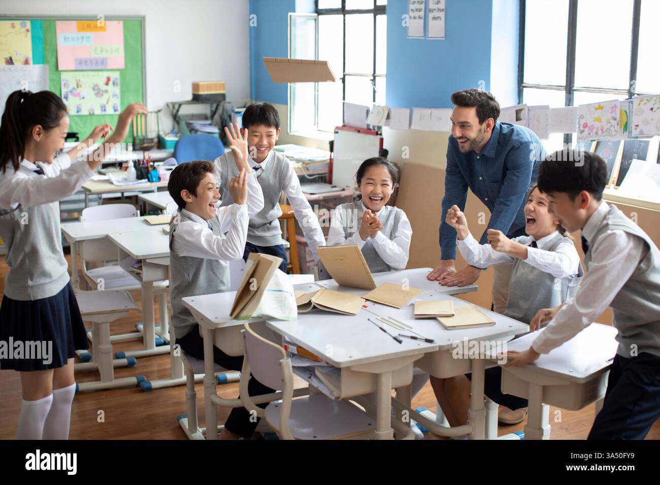 Studenti cinesi e insegnanti maschi caucasici che si divertono durante le lezioni in classe Foto Stock