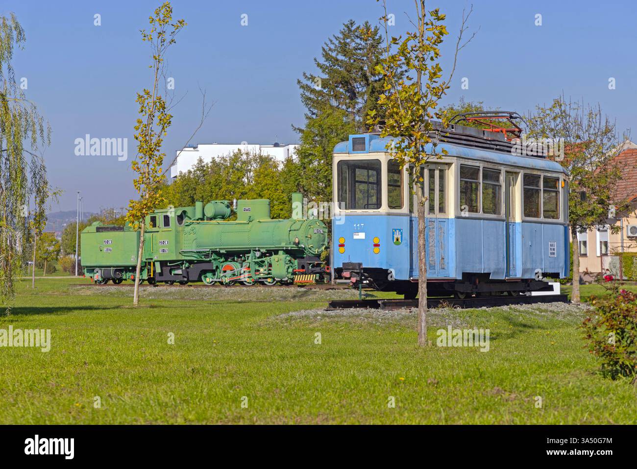 Slavonski Brod, Croazia - 22 ottobre 2024: Locomotiva a vapore e vecchio tram presso il Parco industriale Turistico Djuro Djakovic, Museo all'aperto gratuito. Foto Stock