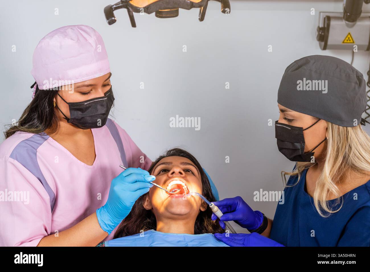Vista dall'alto verso il basso di un'équipe dentale che assiste un paziente durante un controllo di routine con strumenti e apparecchiature dentali esposti. Adatto per i temi della clinica odontoiatrica e sanitaria. Foto Stock