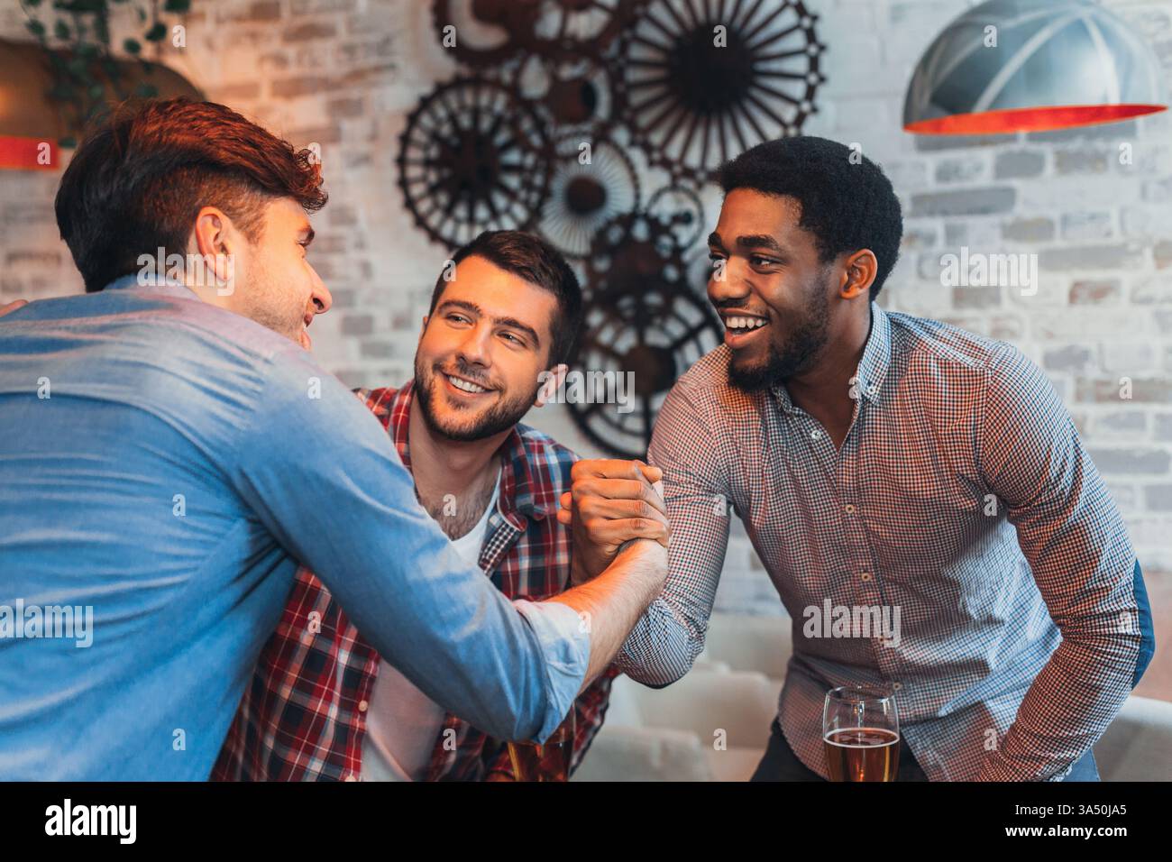 Un gruppo multirazziale di amici condivide un allegro saluto in un vivace pub. Questa variegata scena cattura l'amicizia, socializzazione informale e un'atmosfera rilassata da bar con birra. Foto Stock