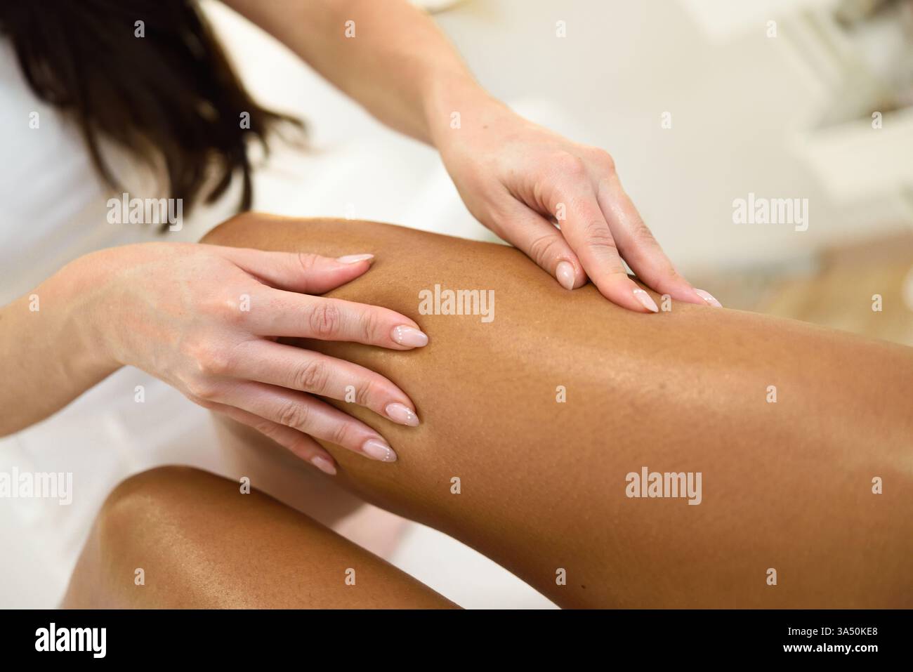 Massaggio alle gambe in un salone di bellezza con applicazione professionale di olio sulla pelle. Ideale per trattamenti termali, benessere e cura della pelle. Ottimo per servizi di bellezza, relax e campagne self-care. Foto Stock
