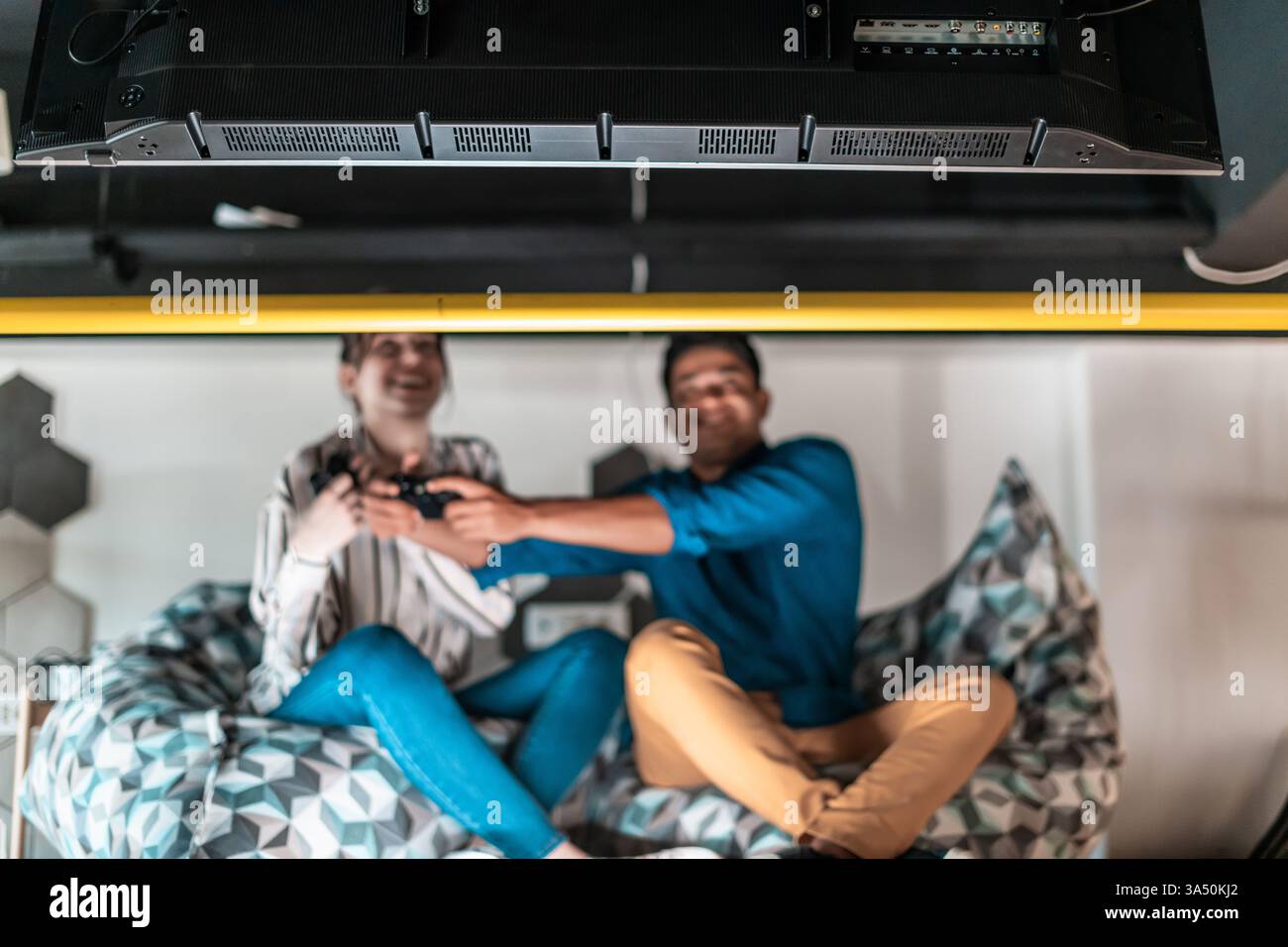 Due colleghi in un ufficio di startup rilassato giocano a un gioco al computer durante una pausa nell'area relax. L'ambiente creativo e informale mette in risalto il lavoro di squadra e l'innovazione. Perfetto per la tecnologia, la cultura delle startup e la pubblicità sul luogo di lavoro. Foto Stock