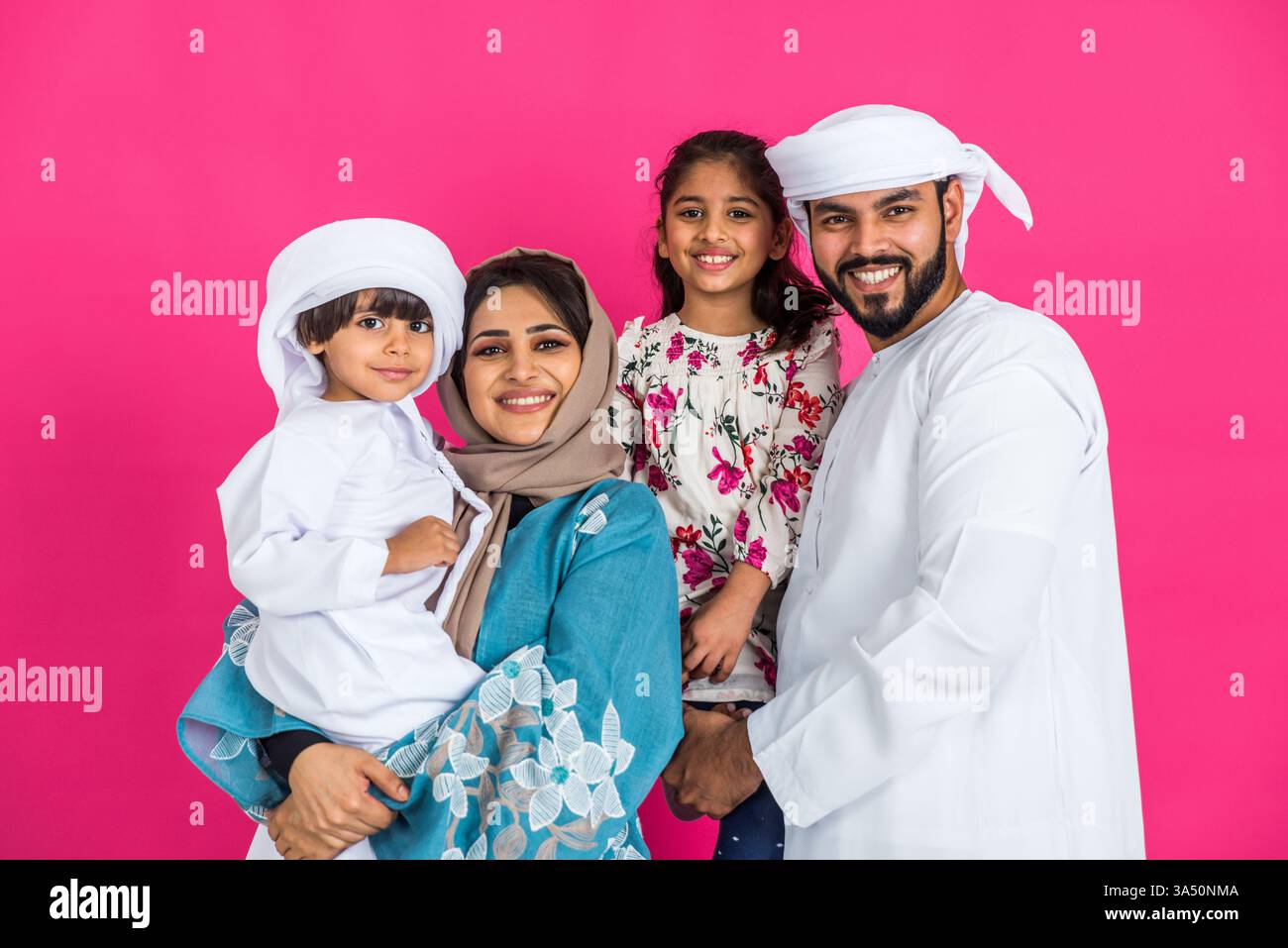 La famiglia mediorientale in abiti tradizionali degli Emirati posa in uno studio fotografico. Una calda rappresentazione dello stile di vita, della felicità e delle relazioni familiari. Adatto per elementi culturali, marchi storici e narrazione regionale. Foto Stock