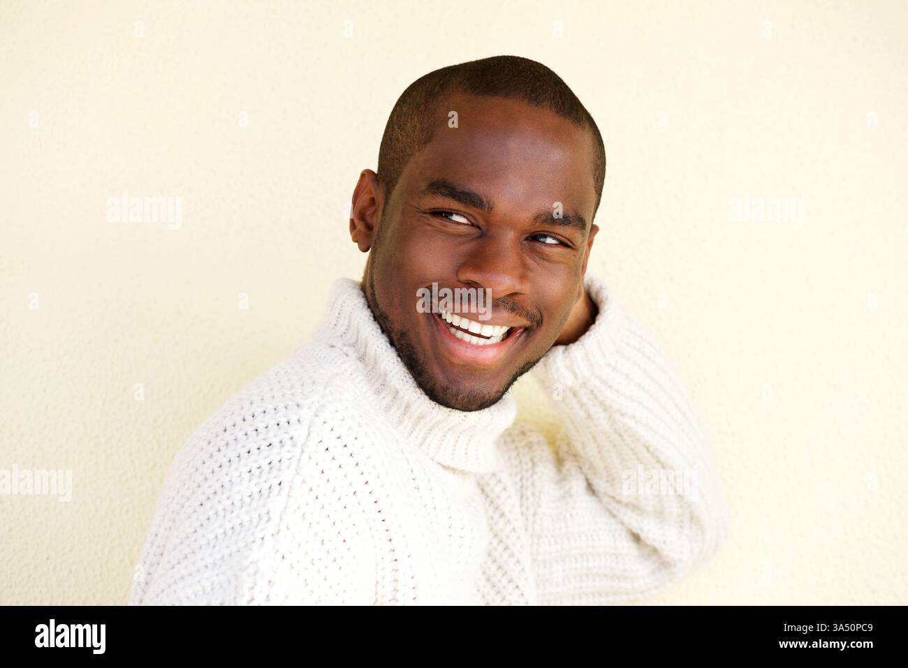 Primo piano ritratto laterale di un attraente uomo afroamericano in un maglione. L'uomo trasuda fiducia e calore in una posa casual ed elegante. Perfetto per lo stile di vita, la moda e i contesti di lavoro moderni con un modello maschile contemporaneo. Foto Stock