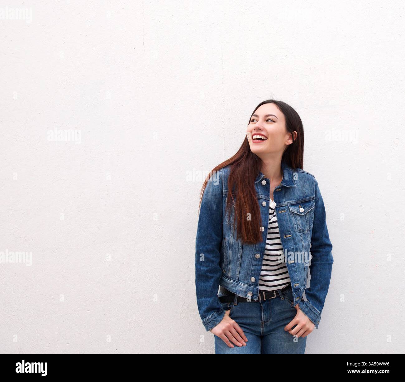 Ritratto di una donna che ride con una giacca in denim. Atmosfera casual ed elegante adatta a campagne di moda, lifestyle e social media. Spazio di testo disponibile per il branding o la messaggistica. Foto Stock