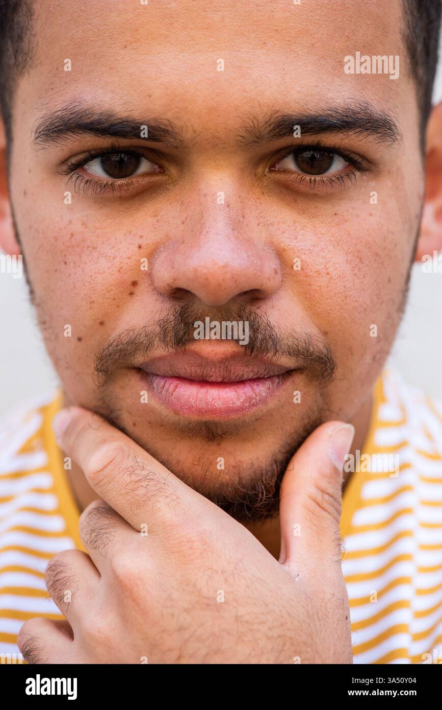 Ritratto ravvicinato di un uomo afroamericano di razza mista con la mano contro il mento. Questa elegante immagine contemporanea è ideale per progetti di lavoro o di stile di vita. Foto Stock