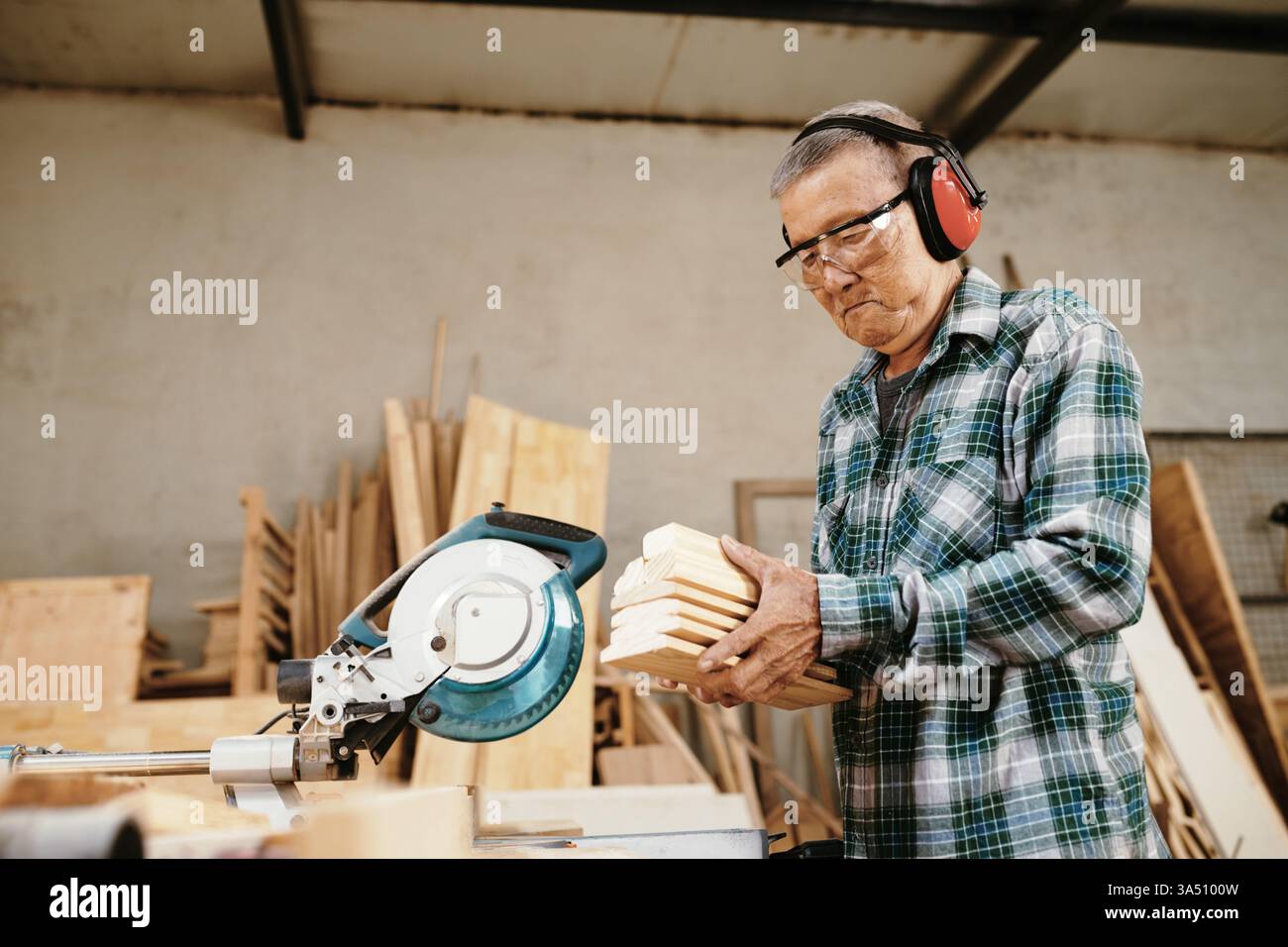 Falegname professionale che porta tavole di legno sul banco da lavoro per tagliare con una sega circolare. Ideale per l'edilizia, la carpenteria e le immagini di mestieri specializzati. Foto Stock