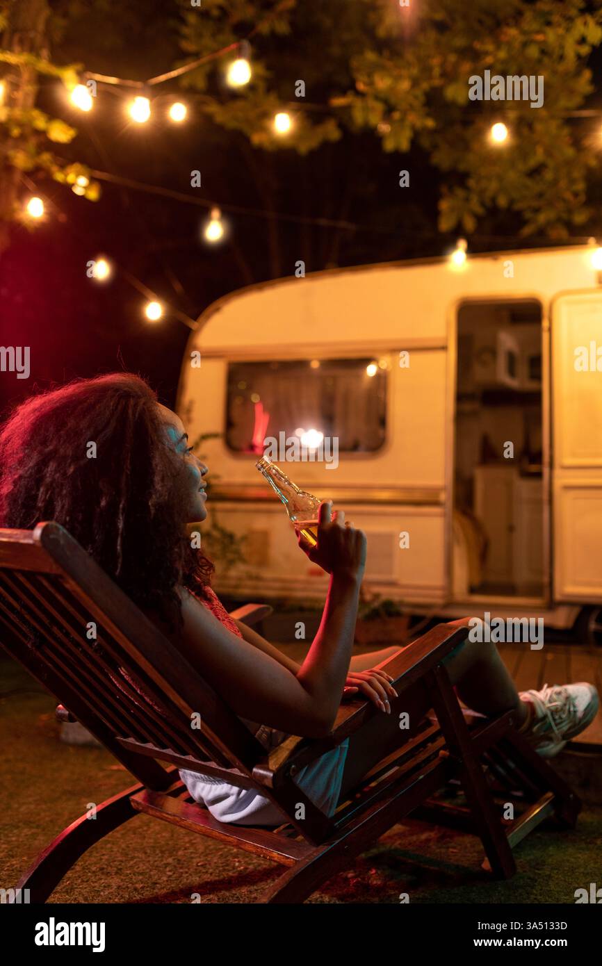 Giovane coppia in vacanza con un camper, godendosi una notte nella natura. Una scena cinematografica a tema vagabondo perfetta per viaggi, viaggi in auto e campagne di lifestyle. Foto Stock