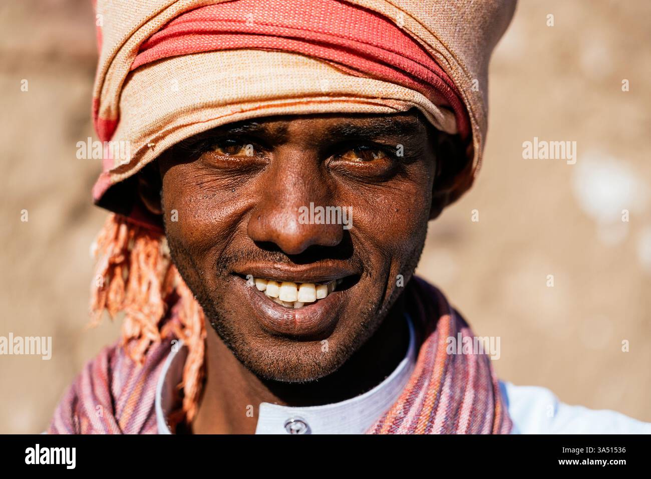 Uomo sorridente del Medio Oriente che indossa il tradizionale turbante in piedi all'aperto nelle giornate di sole Foto Stock