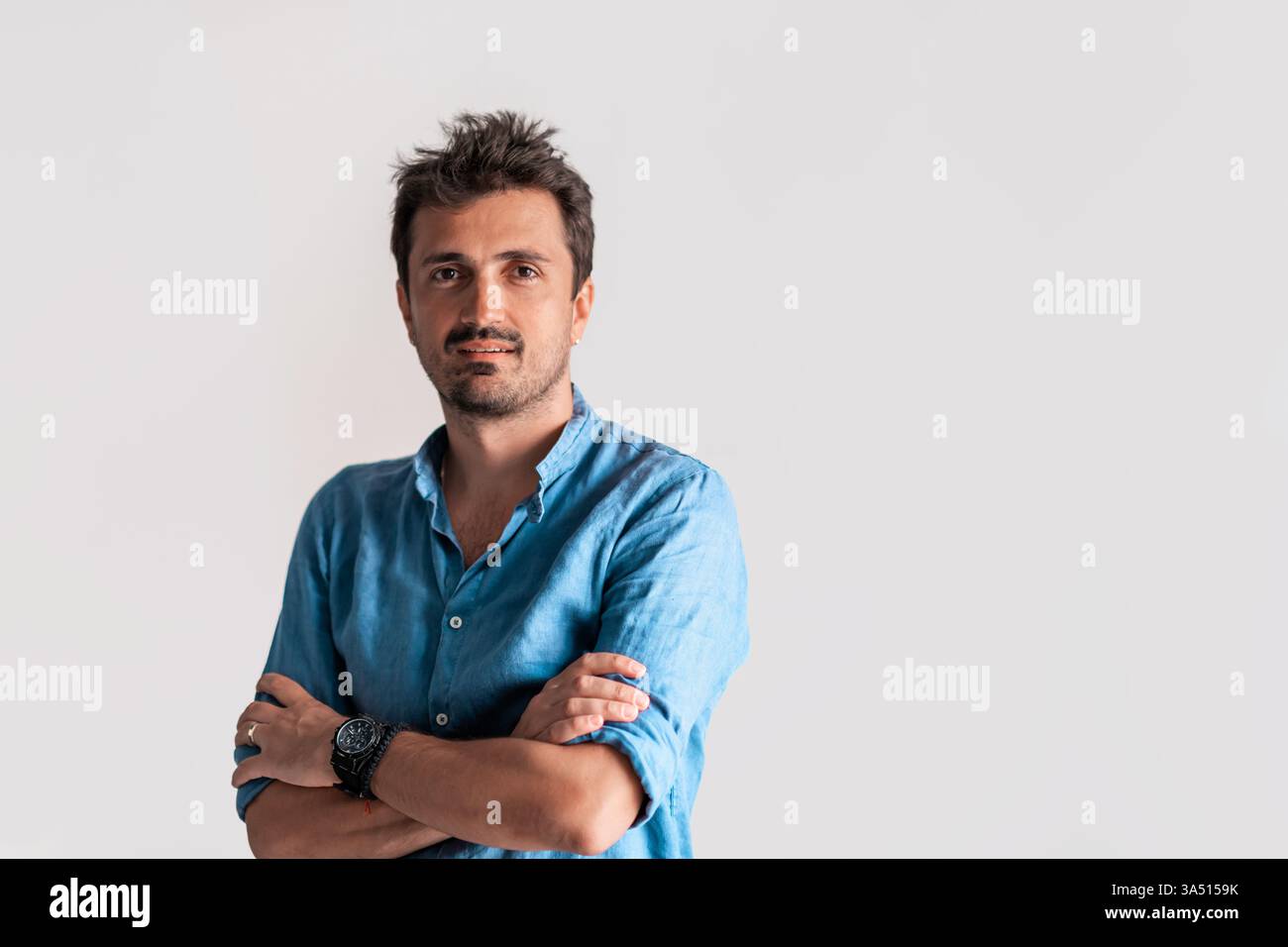 Ritratto aziendale formale di un uomo d'affari fiducioso e informale in piedi con le braccia incrociate su sfondo bianco. Questa immagine professionale trasmette leadership, successo e stile aziendale. Ideale per profili dirigenziali, campagne aziendali e comunicazioni aziendali. Foto Stock