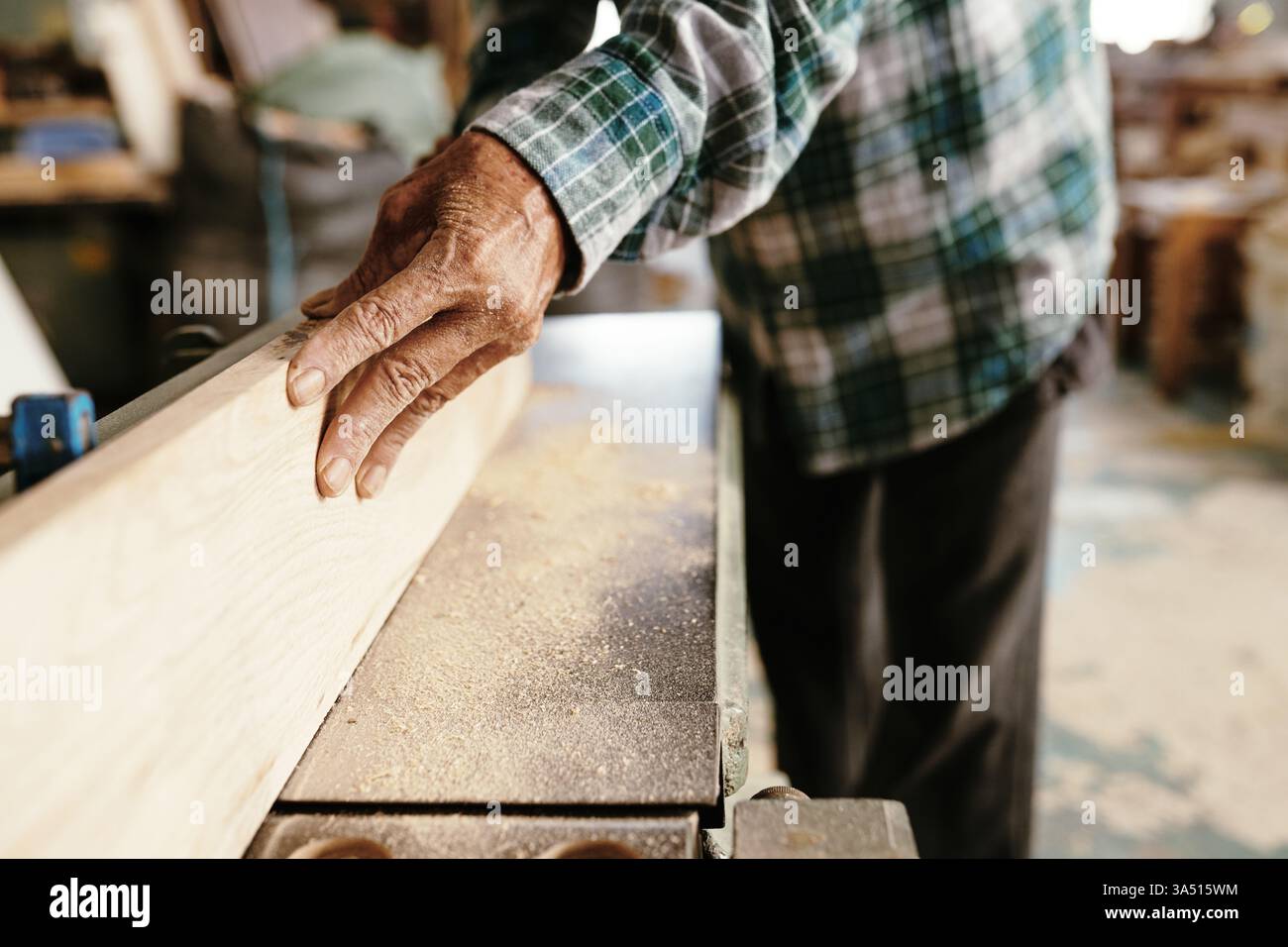 Primo piano di un falegname asiatico anziano che utilizza una falegnameria per planare una superficie piana lungo tavole di legno. Adatto per la lavorazione del legno, la falegnameria e la grafica professionale. Foto Stock