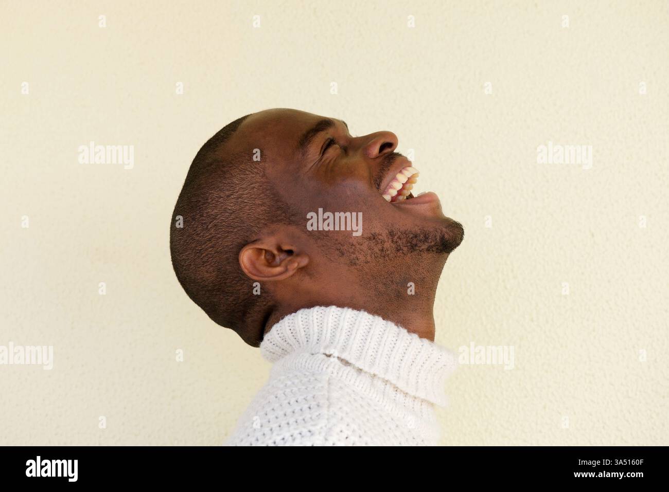 Primo piano ritratto laterale del bell'uomo afroamericano maglione ridendo e guardando in su Foto Stock