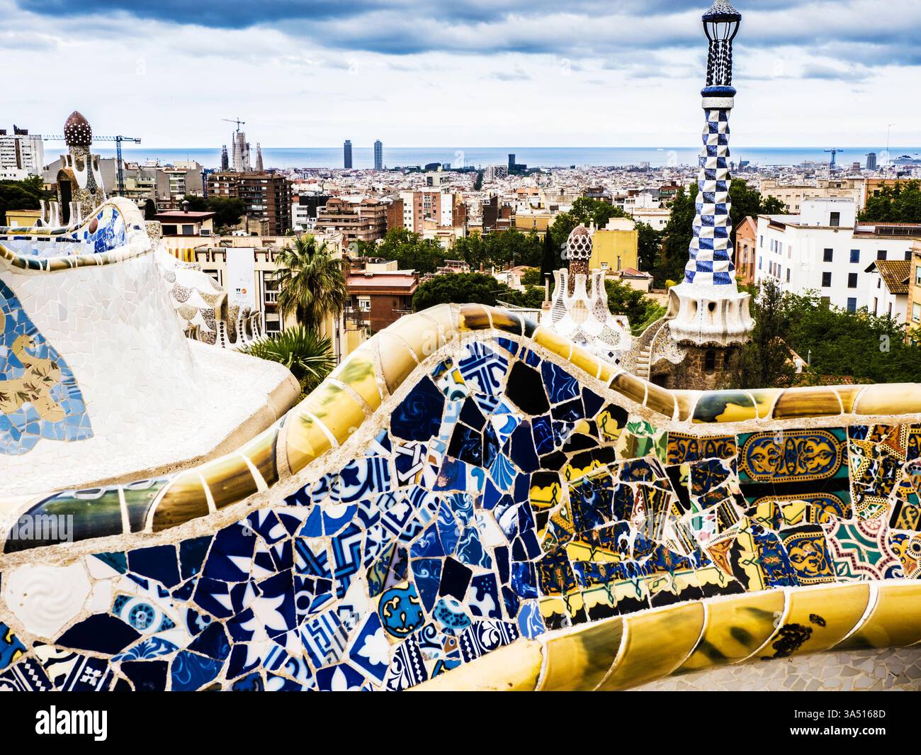 Vista su Barcellona da Piazza natura o Plaza de la natura nel Parc Güell, Barcellona. L'iconica panca piastrellata è in primo piano e la Sagrada Fami Foto Stock