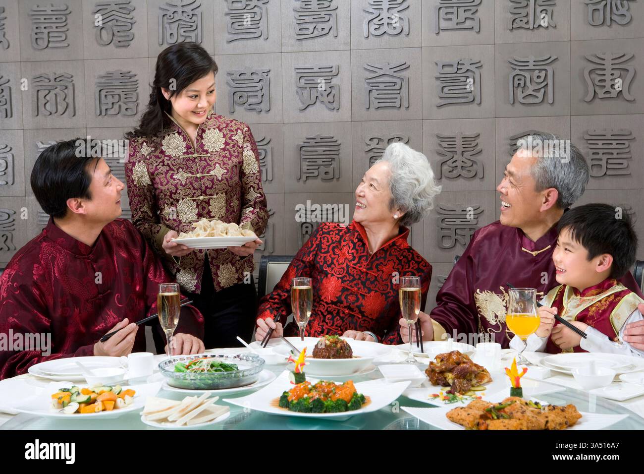 Gioiosa cena per famiglie cinesi in un ristorante, festeggiando insieme al chiuso. Risate e insieme creano una scena gastronomica festosa, adatta a feste di famiglia o a cucine. Foto Stock