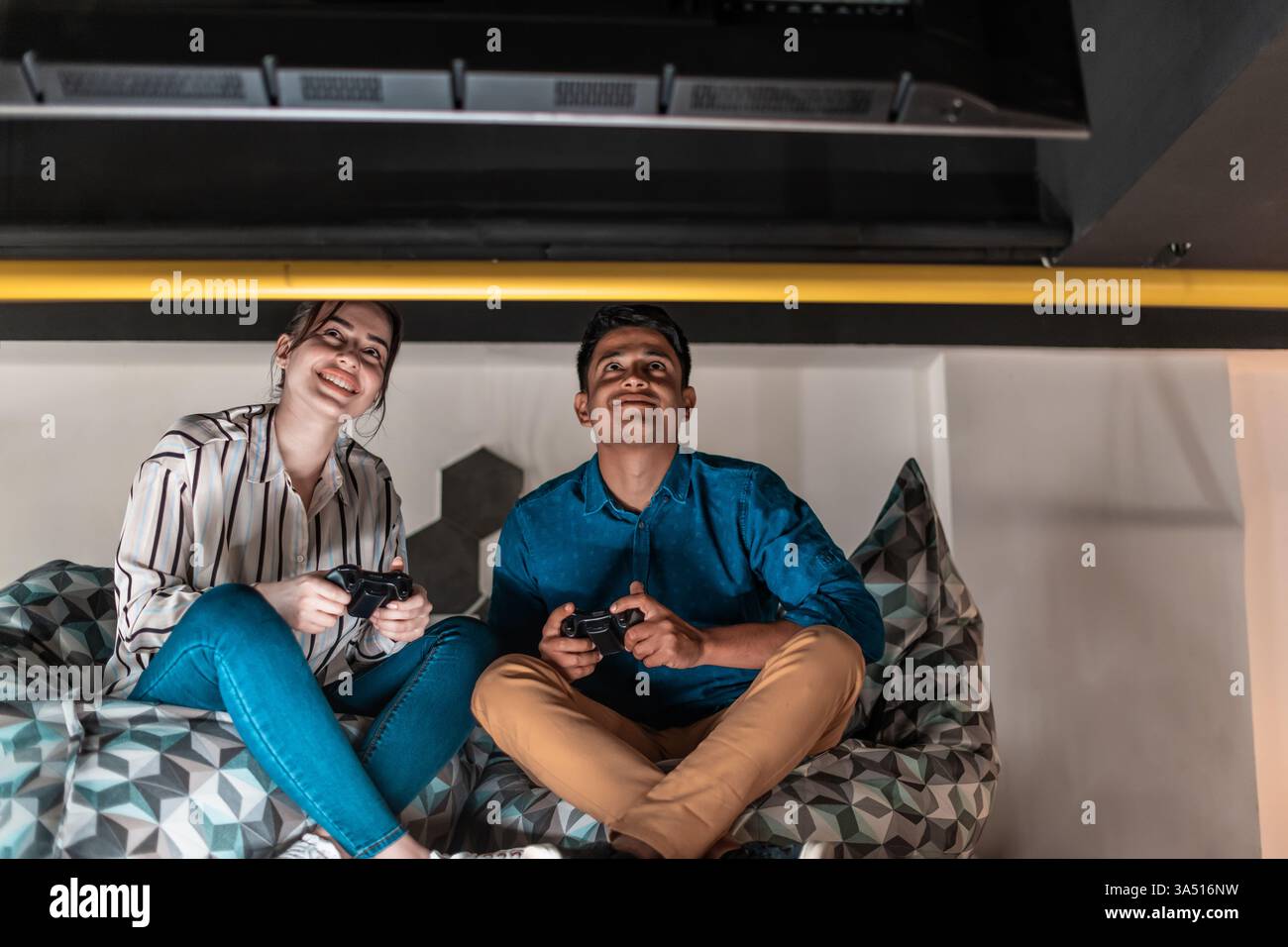 Ambiente di lavoro informale all'avvio con colleghi che giocano ai videogame durante una pausa. Un team eterogeneo compete in uno spazio di lavoro moderno e rilassato, mettendo in risalto il lavoro di squadra e la creatività. Foto Stock