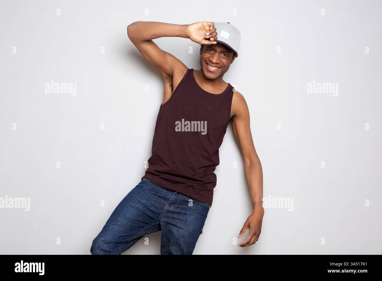 L'allegro afroamericano che indossa un berretto si erge su uno sfondo bianco. Il ritratto pulito offre un ampio spazio di copia, perfetto per il branding, la pubblicità o l'uso aziendale con un'atmosfera casual ed elegante. Foto Stock