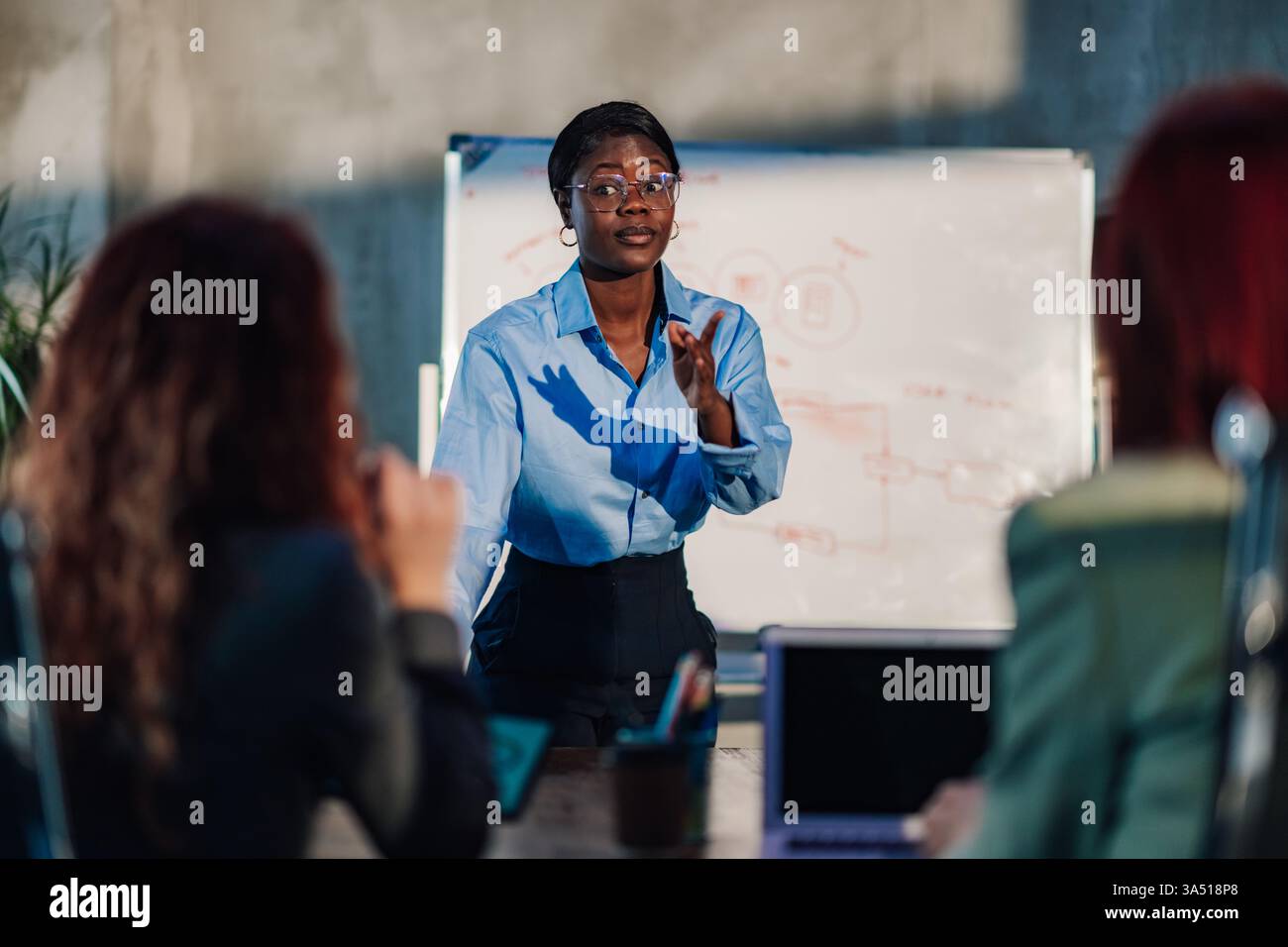 Manager multiculturale che tiene un briefing e discute di strategia aziendale e idee di marketing nella sala riunioni con il suo team. africano professionale Foto Stock