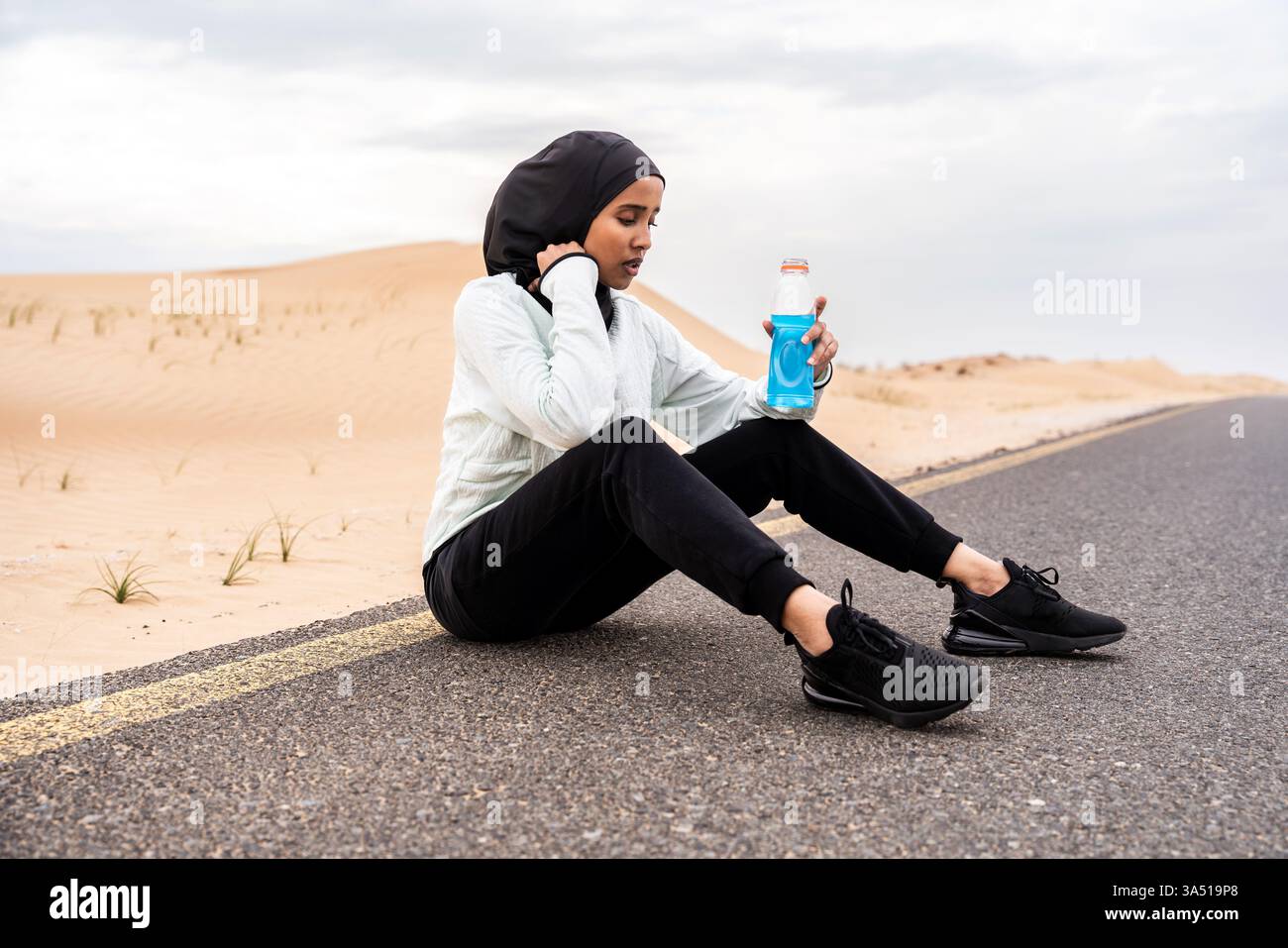 Gli allenamenti all'aperto nel deserto includono un atleta musulmano che indossa hijab e burkini. La scena mostra fitness e vita attiva in un ambiente caldo e arido. Foto Stock