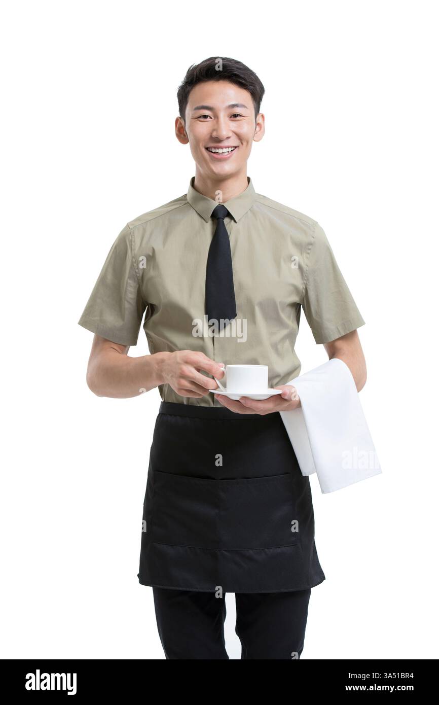 Il sorridente cameriere cinese tiene una tazza di caffè con un asciugamano avvolto sul braccio in un ambiente da studio. Lo sfondo bianco e pulito enfatizza l'ospitalità e il servizio. Ideale per la grafica di caffè, ristoranti e industria alimentare e delle bevande. Foto Stock