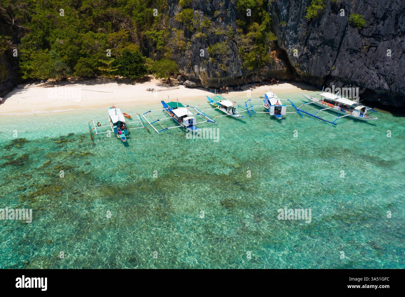 Vista aerea delle barche parcheggiate su una spiaggia tropicale turchese a Palawan, Filippine. Questa immagine di viaggio cattura il paradiso dell'isola, il paesaggio dell'oceano e le vibrazioni estive. La prospettiva dei droni aggiunge un tocco contemporaneo ai contenuti turistici. Foto Stock