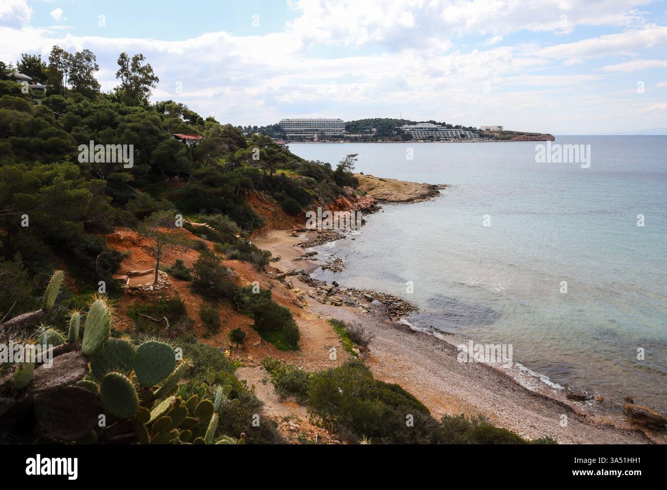 Una fuga costiera nascosta a Paragkes Beach, Vouliagmeni, che presenta una costa frastagliata con acque turchesi cristalline che incontrano le scogliere della terra rossa Foto Stock