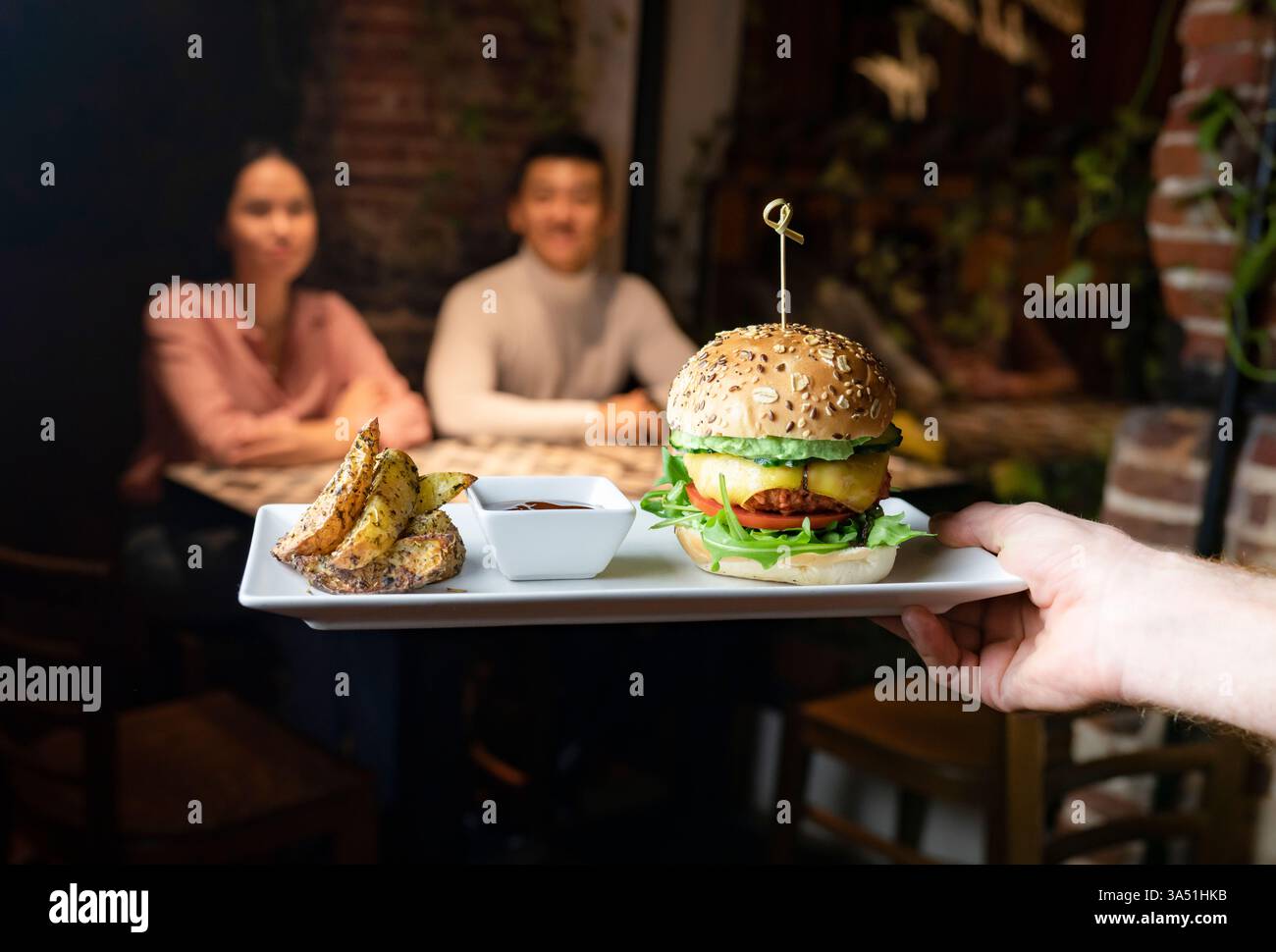Cena informale con hamburger servito con patate al forno e salsa su un vassoio L'immagine trasmette il servizio del ristorante, il pranzo o la cena informali e una presentazione appetitosa. Perfetto per cibo, caffè o ristoranti. Foto Stock