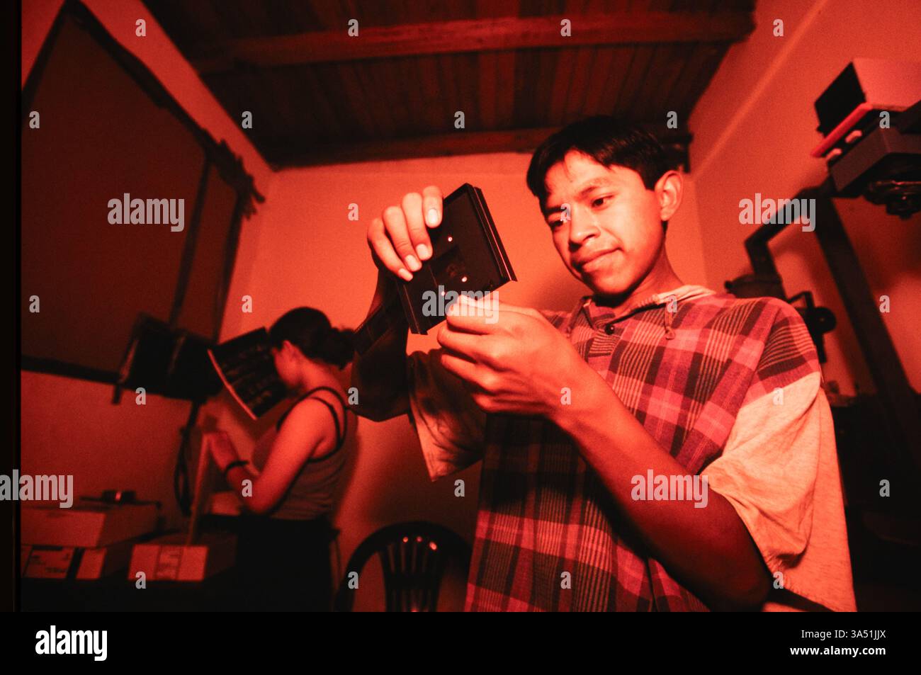 Studenti con la "Mari Sol Photo School" che caricano negativi in un vettore negativo più grande nella camera oscura della scuola, città del Guatemala, Guatemala. Foto Stock