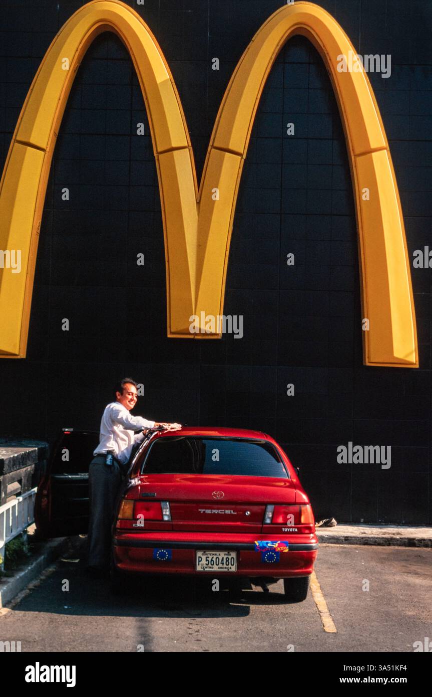 Un autista pulisce la sua auto sotto un cartello McDonald's, Gueatemala City, Guatemala. g Foto Stock