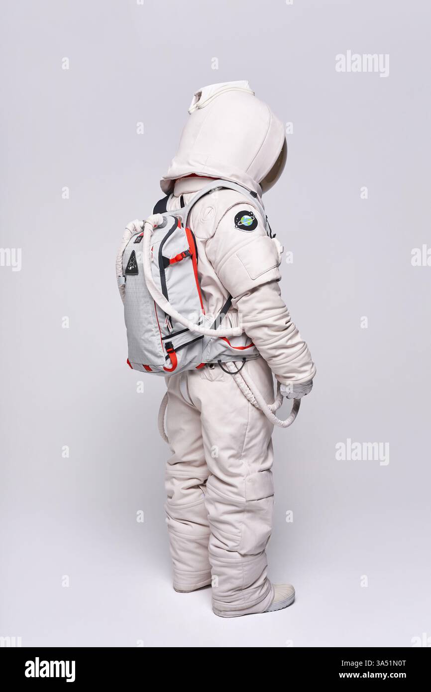 Un astronauta colombiano con tuta spaziale e casco guarda verso il basso su uno sfondo bianco. Questa foto completa in studio trasmette temi di esplorazione spaziale e scienza per progetti di istruzione e tecnologia. Foto Stock